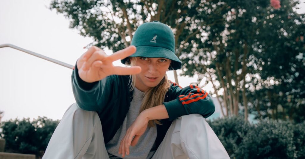 Young woman in casual wear posing with peace sign outdoors.